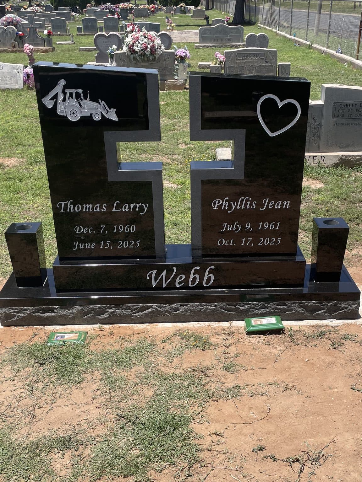 Polished black granite companion headstone with an engraved cross and family name, set at the cemetery