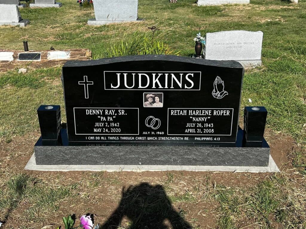 Companion upright granite monument with engraved family scene across the tablet