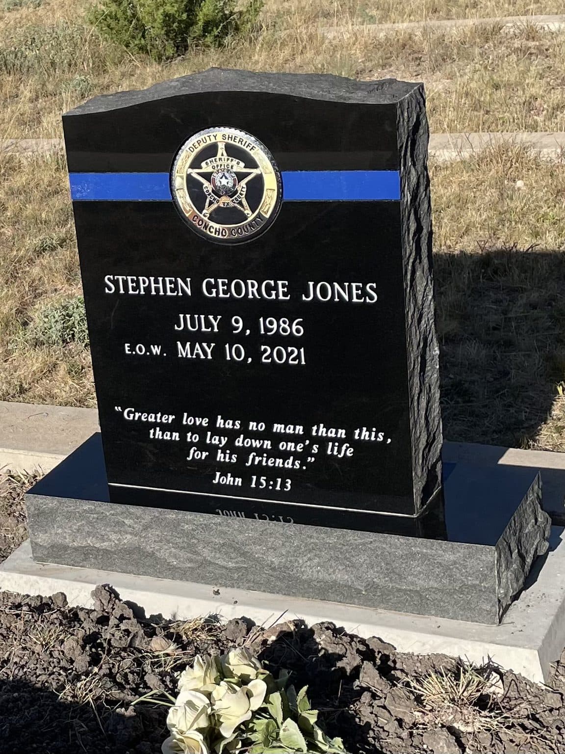 Black granite single upright monument with an engraved star emblem, set at a Texas cemetery
