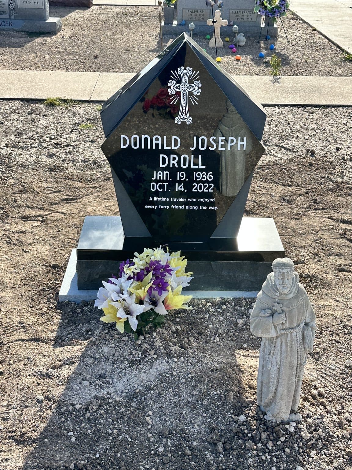 Gray granite single upright monument with an engraved cross, set at a Texas cemetery