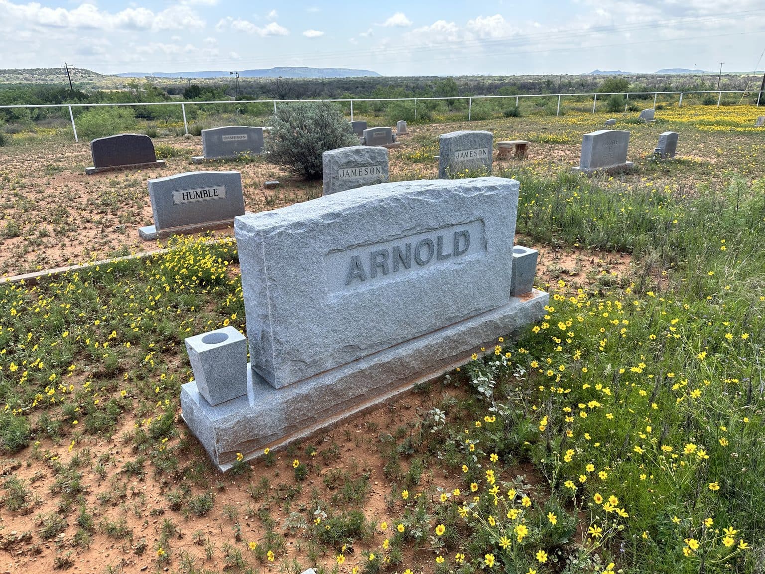 Gray granite companion upright monument set against open Texas hill country