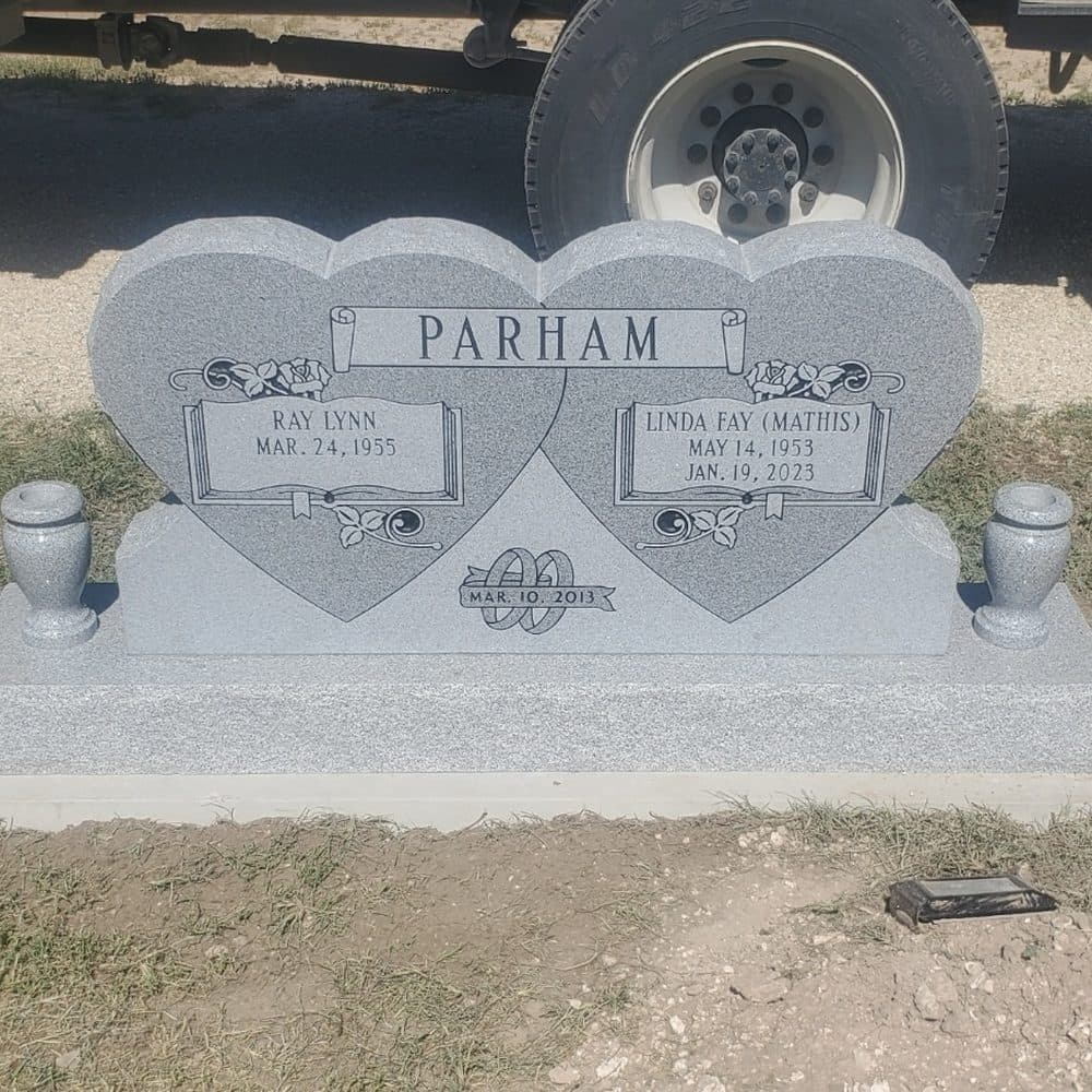 Gray granite companion upright monument with twin engraved hearts, set at a Texas cemetery