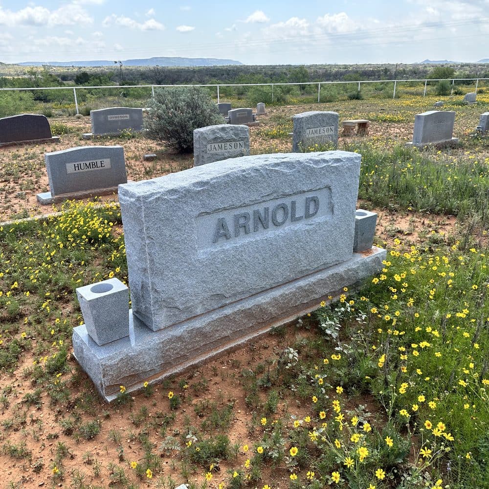 Gray granite companion upright monument set against open hill country, set at a Texas cemetery