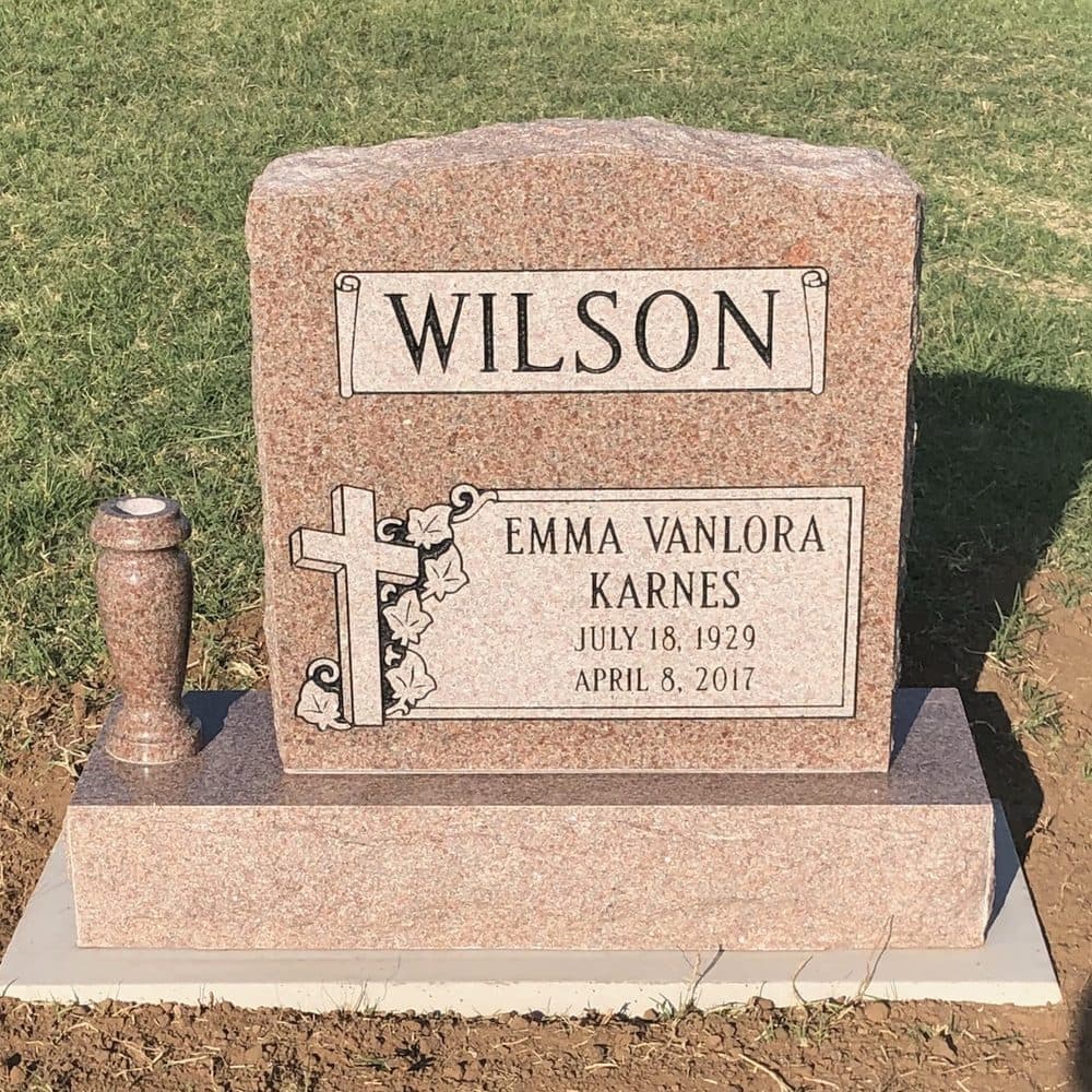 Pink granite single upright monument with a classic serpentine top, set at a Texas cemetery