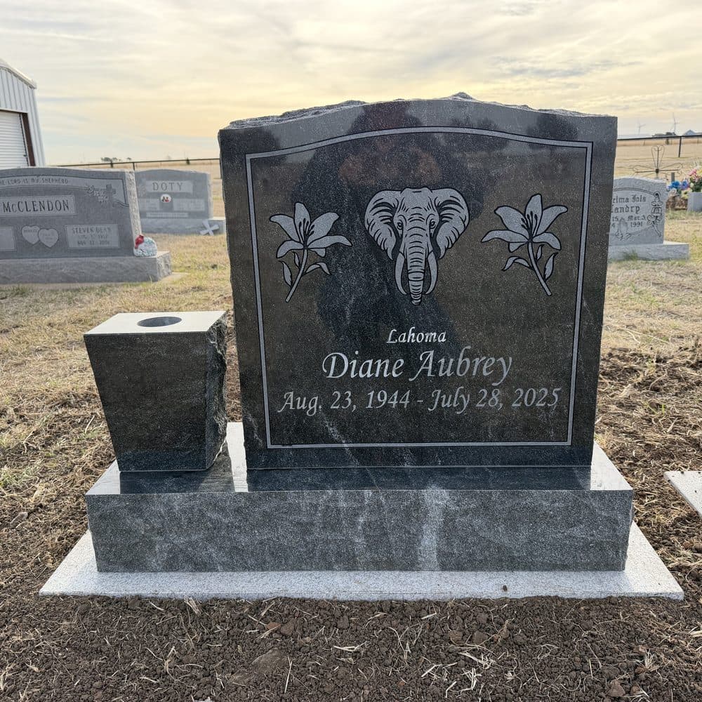 Black granite single upright monument with an engraved nature scene, set at a Texas cemetery