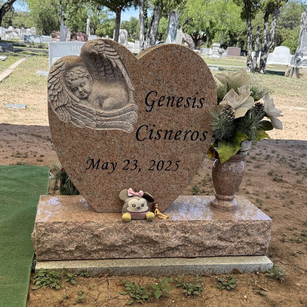 Gray granite single upright monument with an engraved heart and angel, set at a Texas cemetery