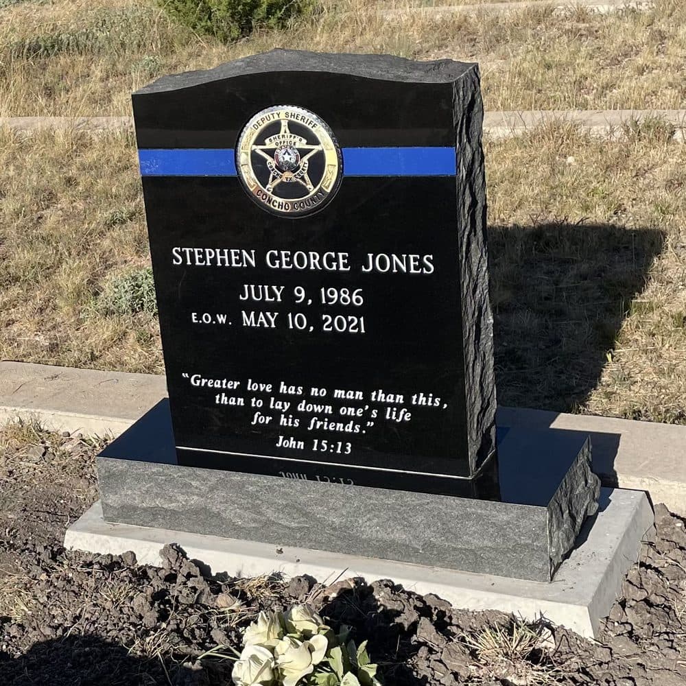 Black granite single upright monument with an engraved star emblem, set at a Texas cemetery