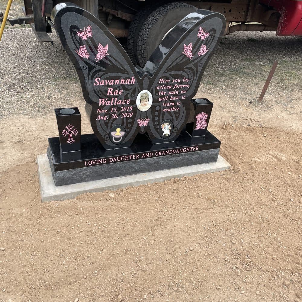 Black granite single upright monument with twin engraved hearts, set at a Texas cemetery