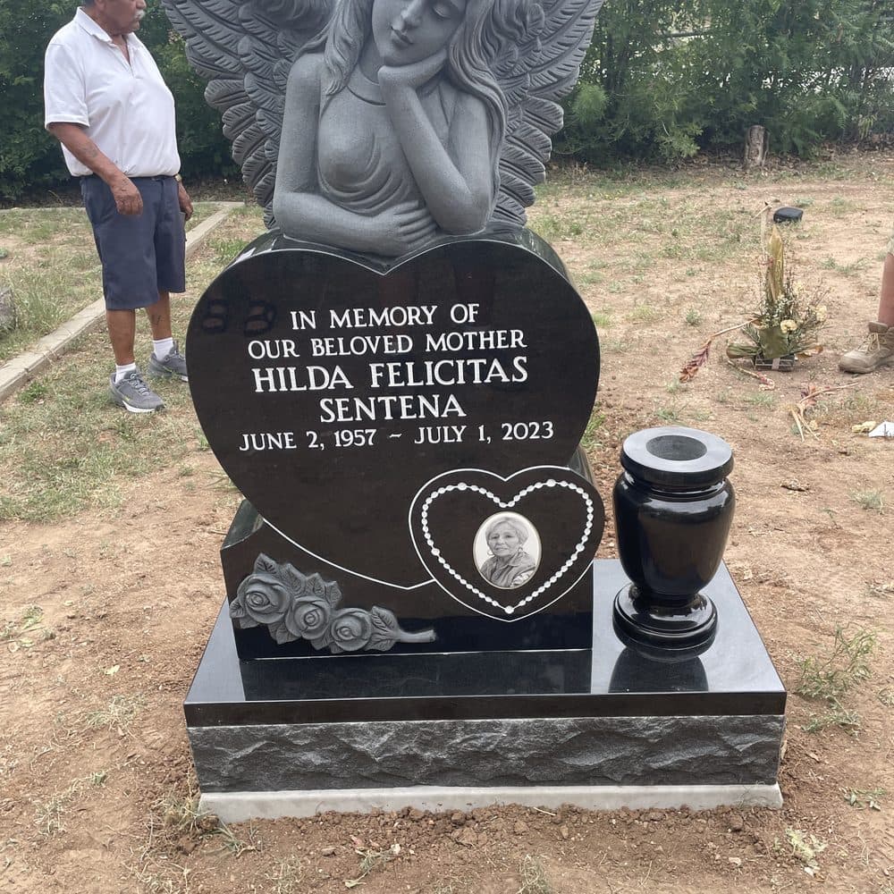 Black granite single upright monument with a sculpted angel and photo heart, set at a Texas cemetery