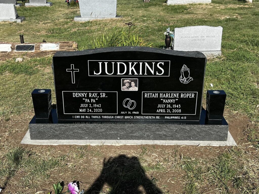 Companion upright granite monument with engraved family scene across the tablet