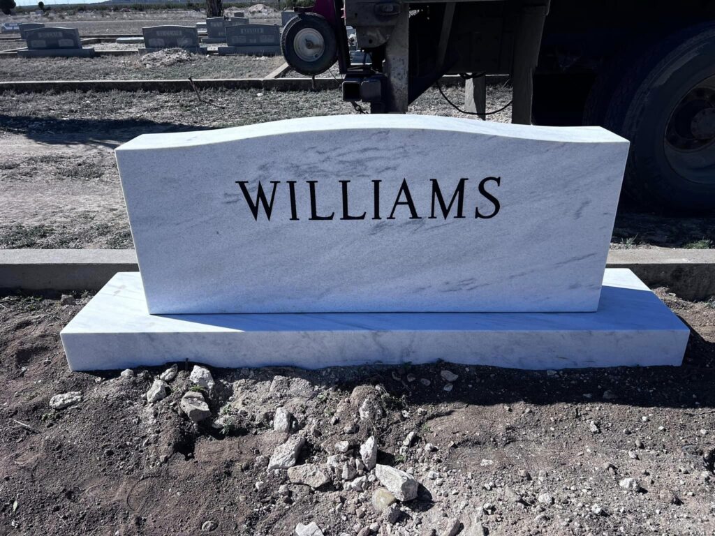Polished black granite single upright with engraved Texas landscape across the back panel